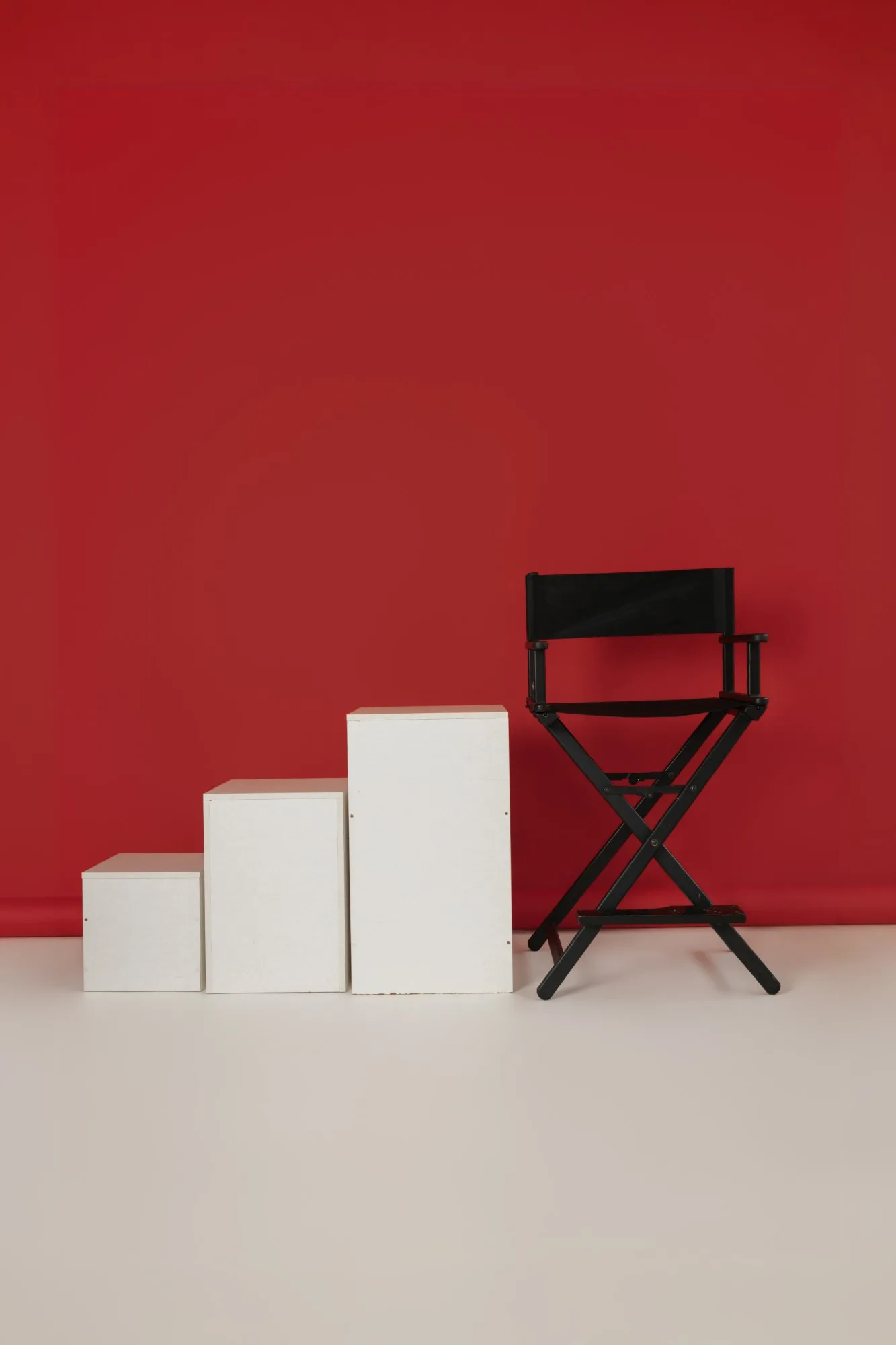Fundo vermelho com caixotes brancos e cadeira de diretor