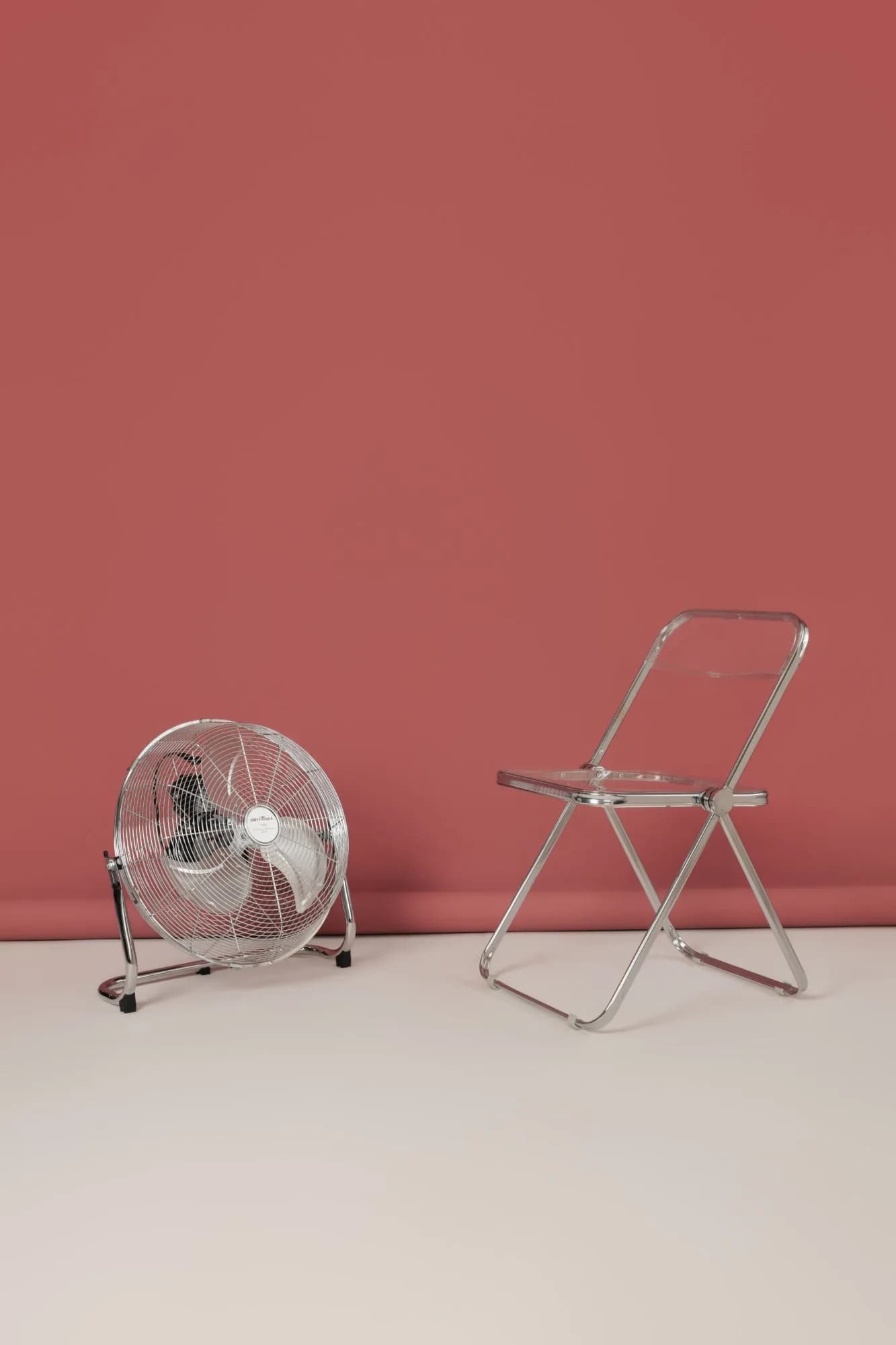 Fundo rosa com ventilador e cadeira transparente